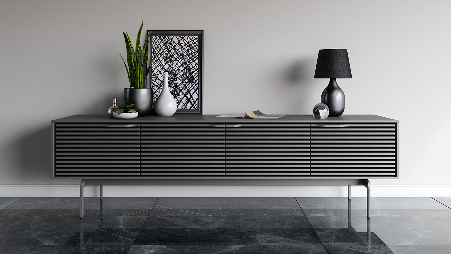 Modern black entertainment console with decorative items against a gray wall.