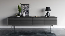 Modern black entertainment console with decorative items against a gray wall.