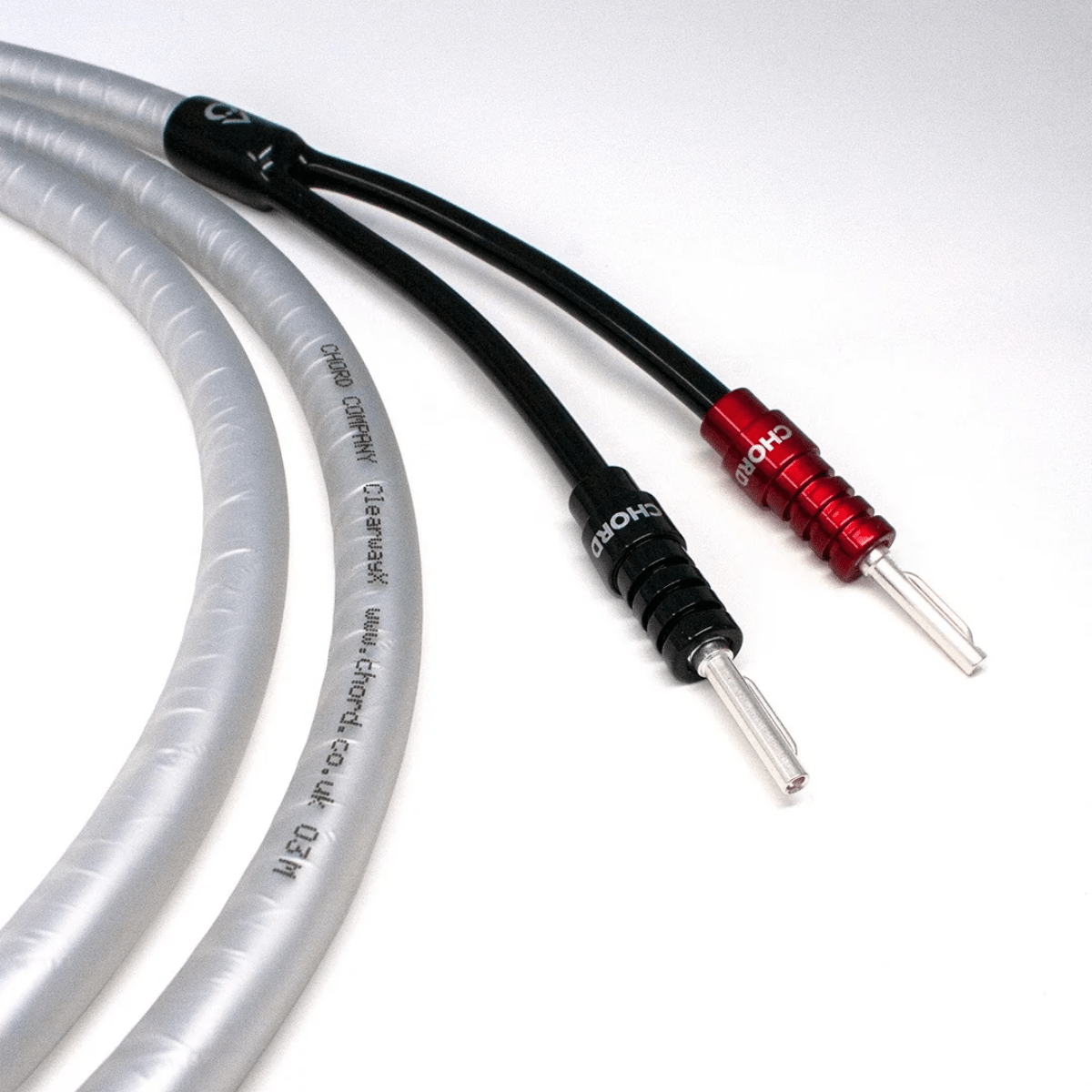 Close-up of Chord ClearwayX speaker cable showing the printed translucent outer jacket and red and black ChordOhmic banana plugs