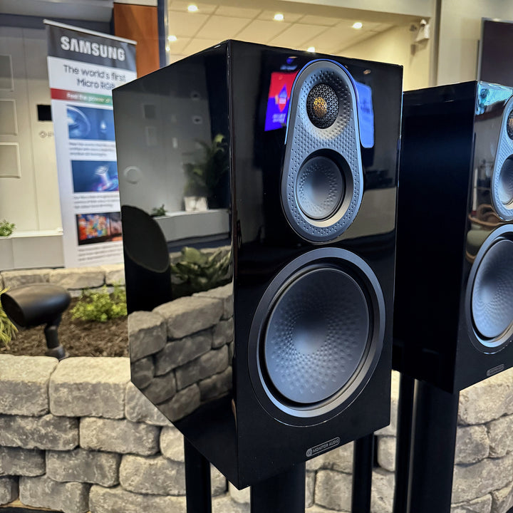 Close-up of a Monitor Audio Silver 8G bookshelf speaker in gloss black, showing the textured tweeter and midrange pod and bass cone