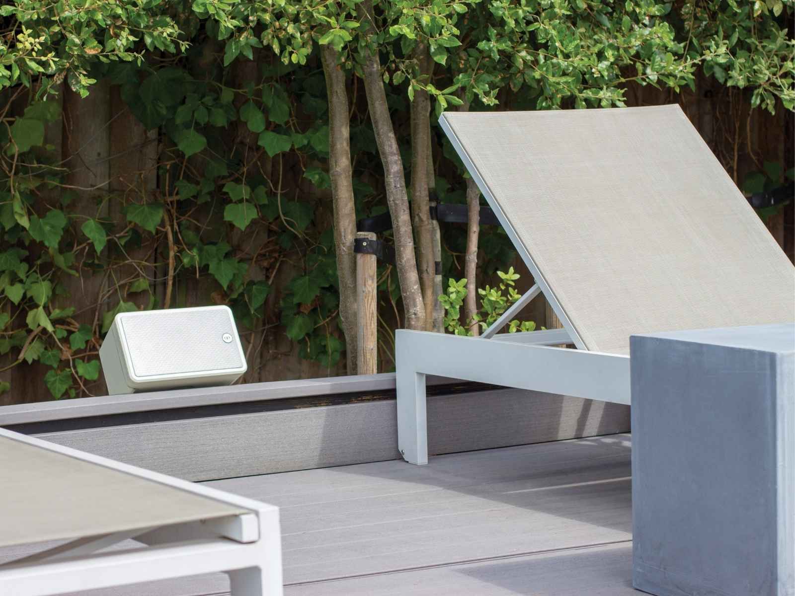 white outdoor speaker by the pool with a reclining chair