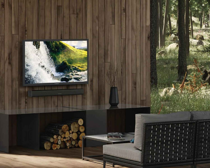 tv and soundbar mounted on a wall outside with chair in front of it