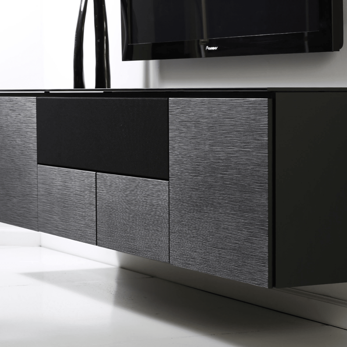 Modern entertainment console with a television mounted on a white wall.