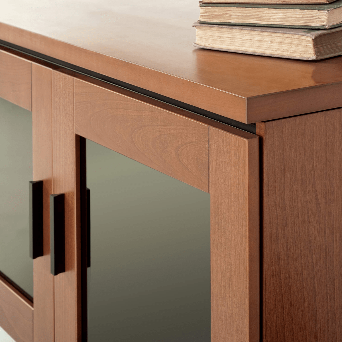 Wooden cabinet with glass doors and a stack of books on top