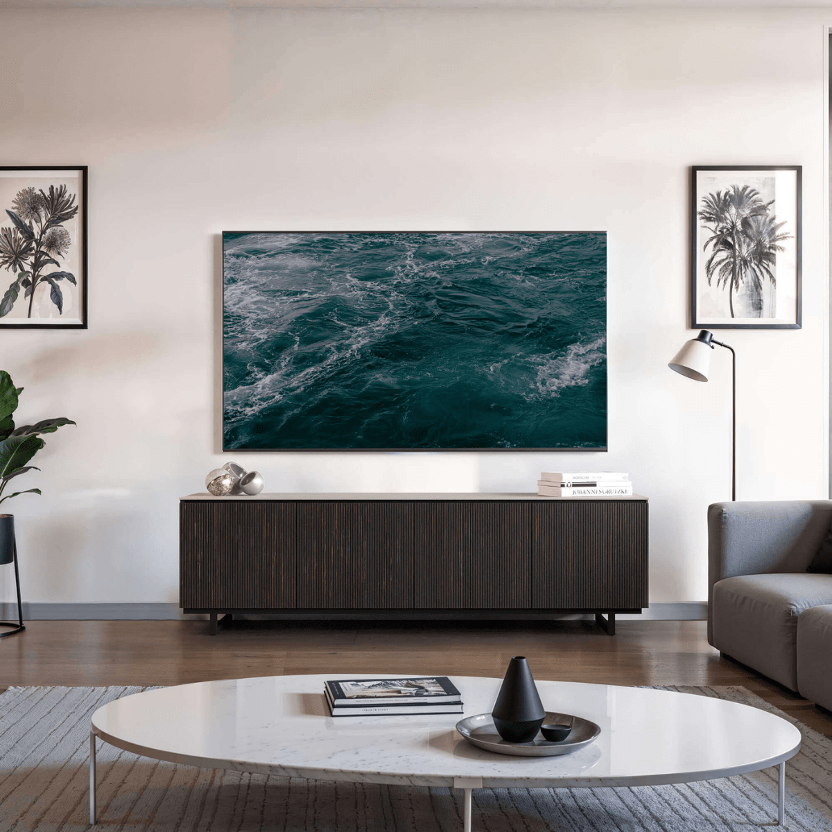Modern living room with a television displaying ocean scenery, a wooden cabinet, and decorative items.