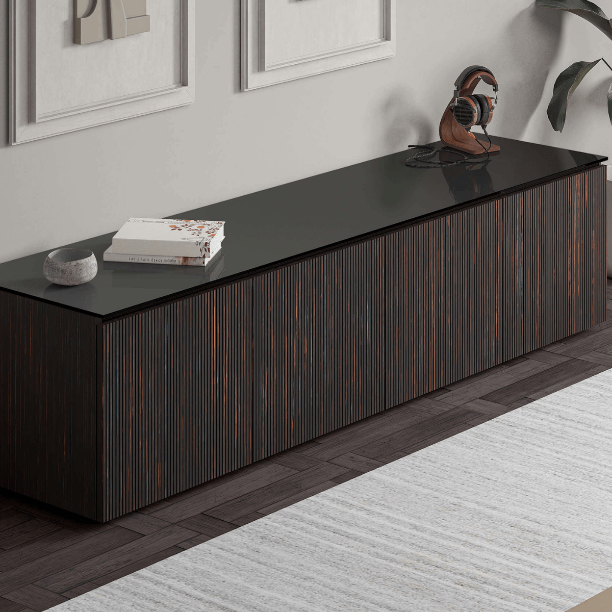 Dark wood entertainment console with black top in a room with framed pictures and a rug.