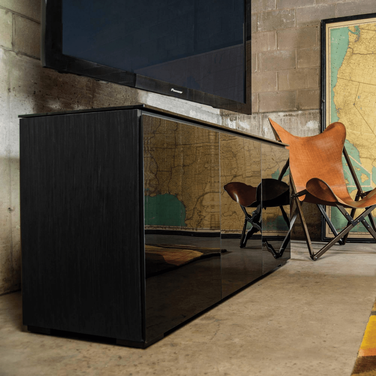 Modern interior with a black cabinet, television, and chairs against a textured wall.
